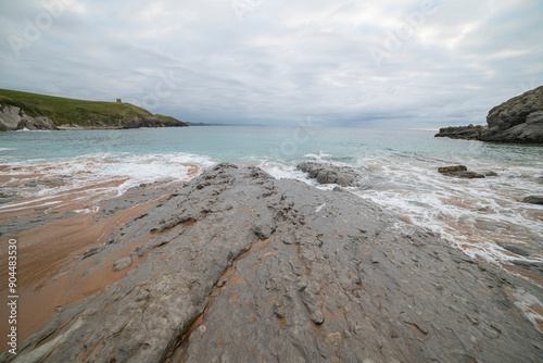 Tranquil scene of Tagle Beach in Cantabria, Spain, showcasing rugged rocks, gentle waves, and an expansive horizon. Perfect for travel, nature, and coastal themes. photo