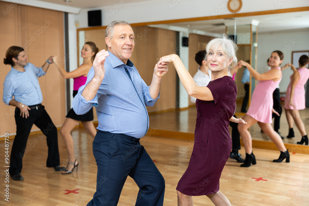 Fototapeta premium Couple of mature dancers rehearsing ballroom dances in dance studio