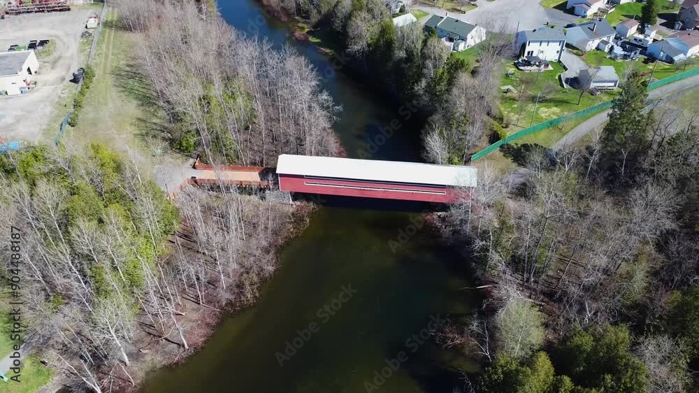 Descente d'un drone vers un petit pont couvert rouge à la toiture blanche traversant la rivière Matapédia, Amqui, Vallée de la Matapédia,Québec.