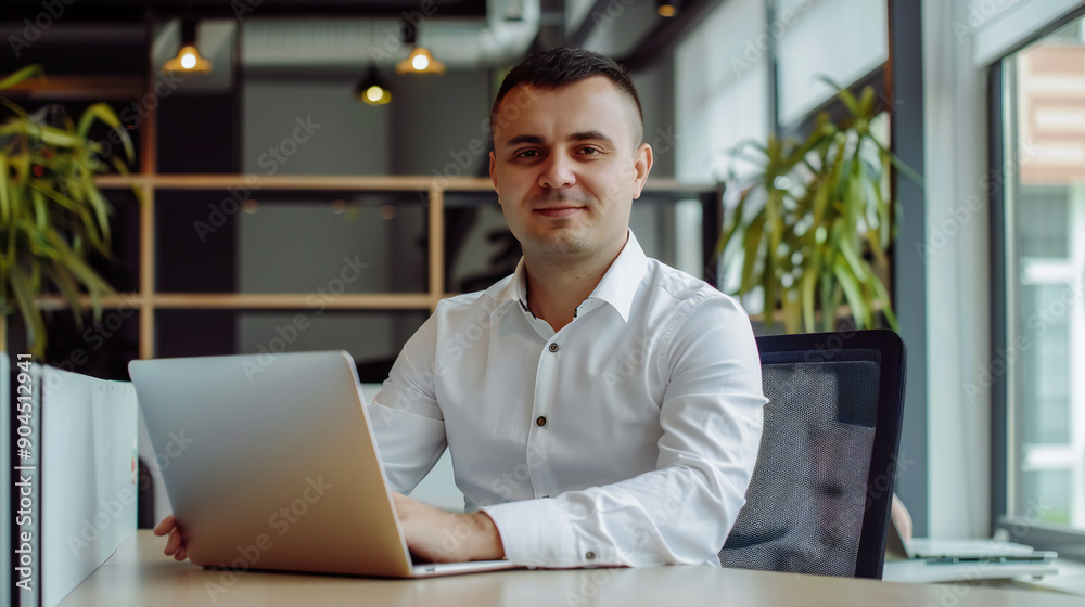 Portrait of a successful male businessman working in his offices with laptop.