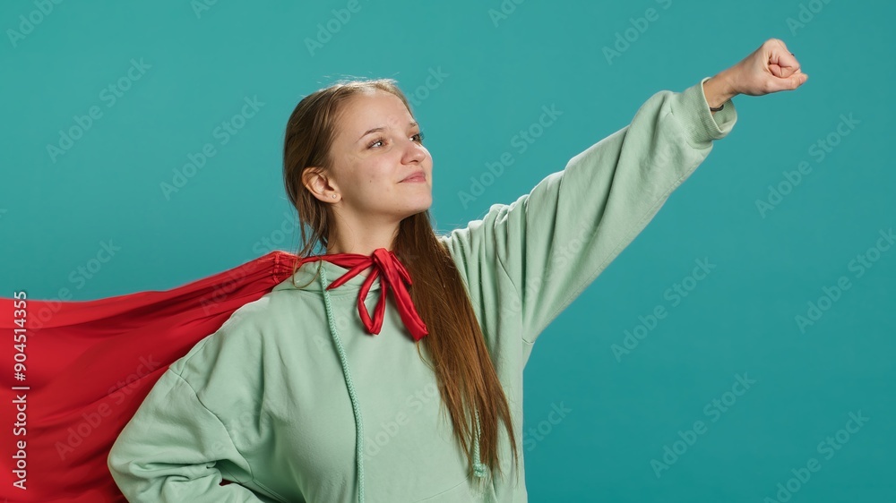 Portrait of jolly girl wearing superhero costume for Halloween, isolated over studio backdrop. Radiant teenage person dressed as comic book hero for event, showing courage and strength, camera A Portrait of jolly girl wearing superhero costume for Halloween, isolated over studio backdrop. Radiant teenage person dressed as comic book hero for event, showing courage and strength, camera A