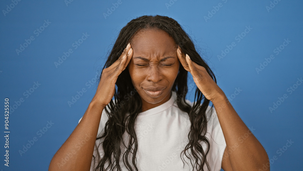African american woman with curly hair wearing a white shirt showing headache against a blue background. African american woman with curly hair wearing a white shirt showing headache against a blue background.