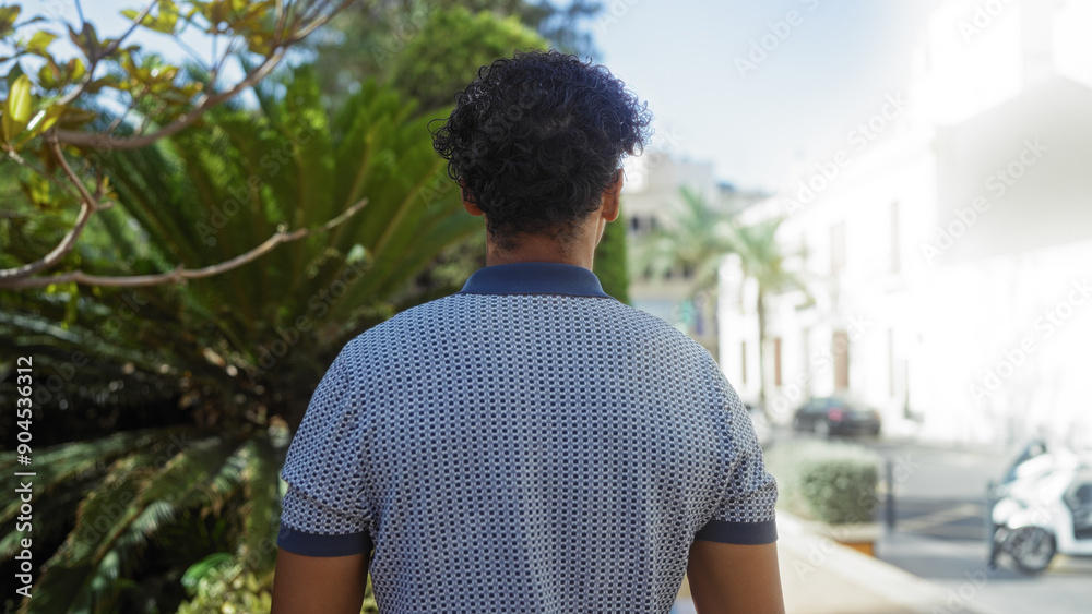 Fototapeta premium Man standing in urban park with lush plants and city buildings in background during daytime