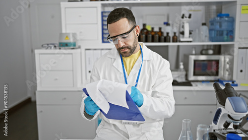 Hispanic man in lab coat examines documents in a well-equipped laboratory, portraying a professional medical or scientific setting.