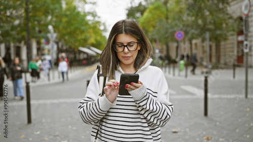 Hispanic woman using smartphone on budapest street photo