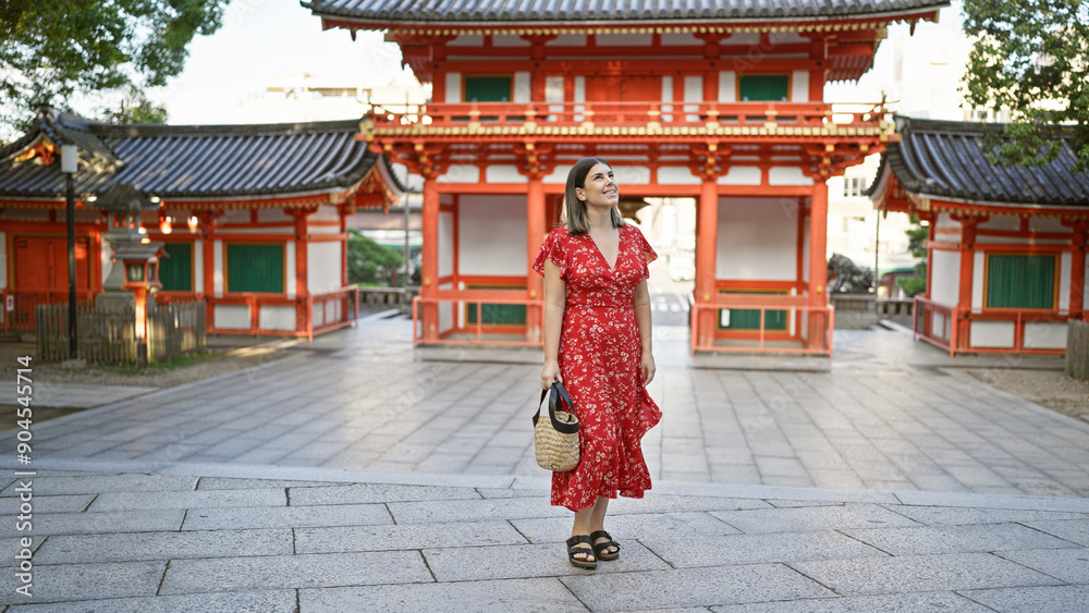 Fototapeta premium Cheerful beautiful hispanic woman enjoying the traditional grandeur of yasaka shrine, joyfully posing and smiling while looking around at the picturesque kyoto temple surroundings.
