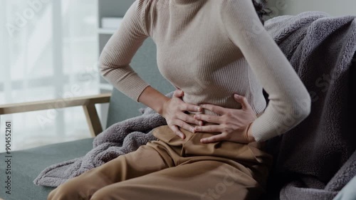 Woman has stomach ache and press hands to stomach due to menstrual cramps period cramps splenomegaly  food poisoning excess gas or acid photo