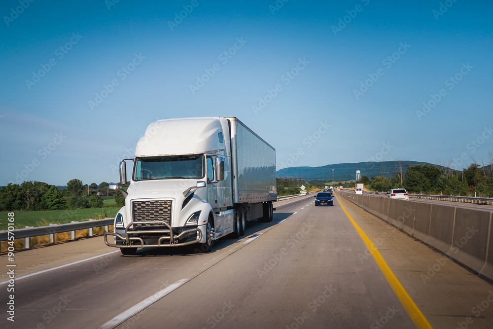 White 18-wheeler semi-truck on the highway delivering freight White 18-wheeler semi-truck on the highway delivering freight