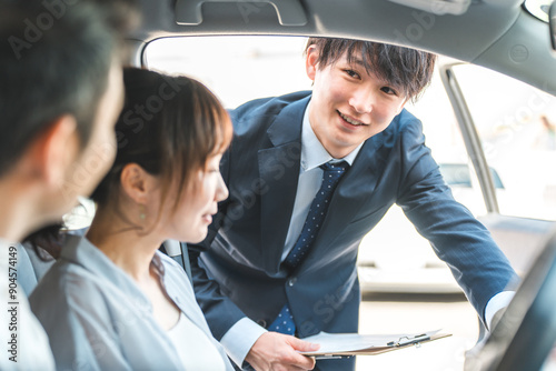 Bild auf Leinwand 自動車購入・査定・買取にきた顧客を接客するセールスマンの若いアジア人男性