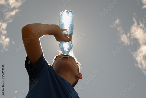 Fotografie Child drinking water from bottle on a hot summer day, thirsty little boy drinks