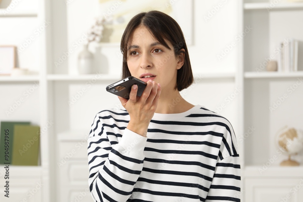 Beautiful woman recording voice message via smartphone at home Beautiful woman recording voice message via smartphone at home