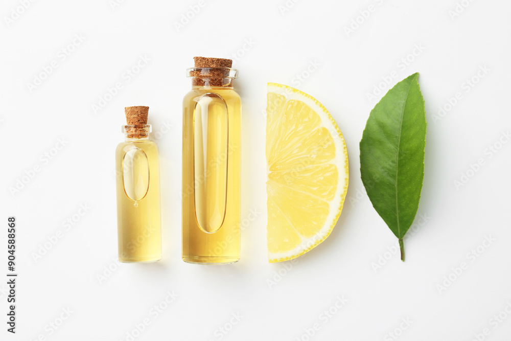 Bottles of essential oils, lemon and green leaf on white background, flat lay Bottles of essential oils, lemon and green leaf on white background, flat lay
