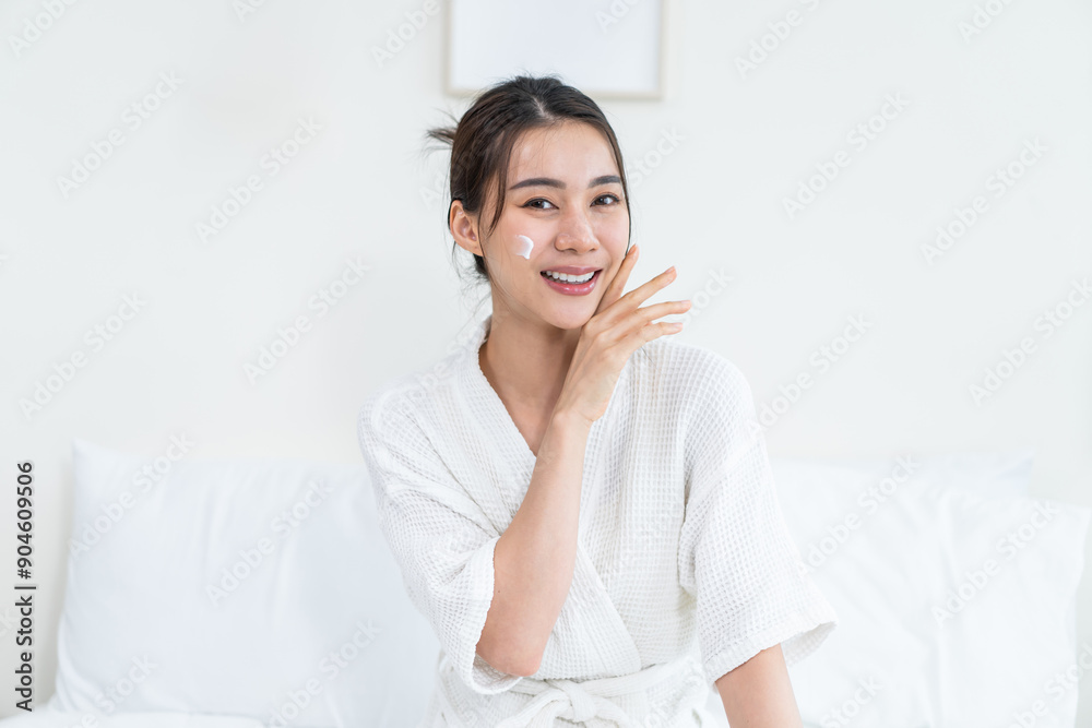 Portrait of Asian woman looking at camera while apply lotion on face. Portrait of Asian woman looking at camera while apply lotion on face.