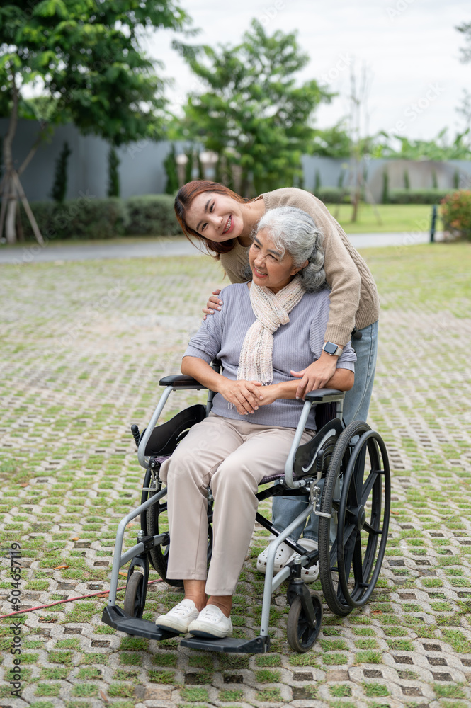 A charming Asian granddaughter and a happy grandmother in a wheelchair are in a park together. A charming Asian granddaughter and a happy grandmother in a wheelchair are in a park together.