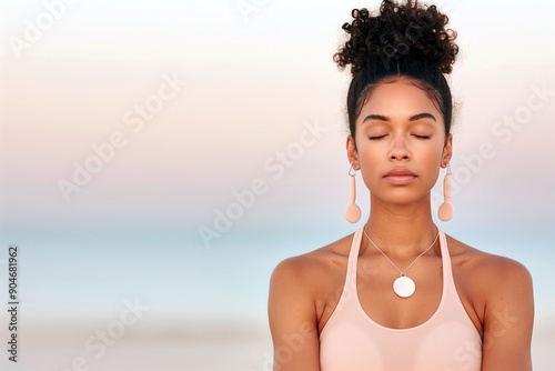 A serene moment captured during a peaceful sunrise meditation session. A woman with closed eyes, radiating calm and focus, set against a soft, pastel-colored sky. For themes of wellness, mindfulness