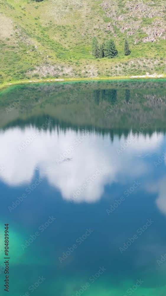 Vertical Aerial video view of Altai mountain lake Uchkol with reflection of blue sky and clouds. Vertical Aerial video view of Altai mountain lake Uchkol with reflection of blue sky and clouds.