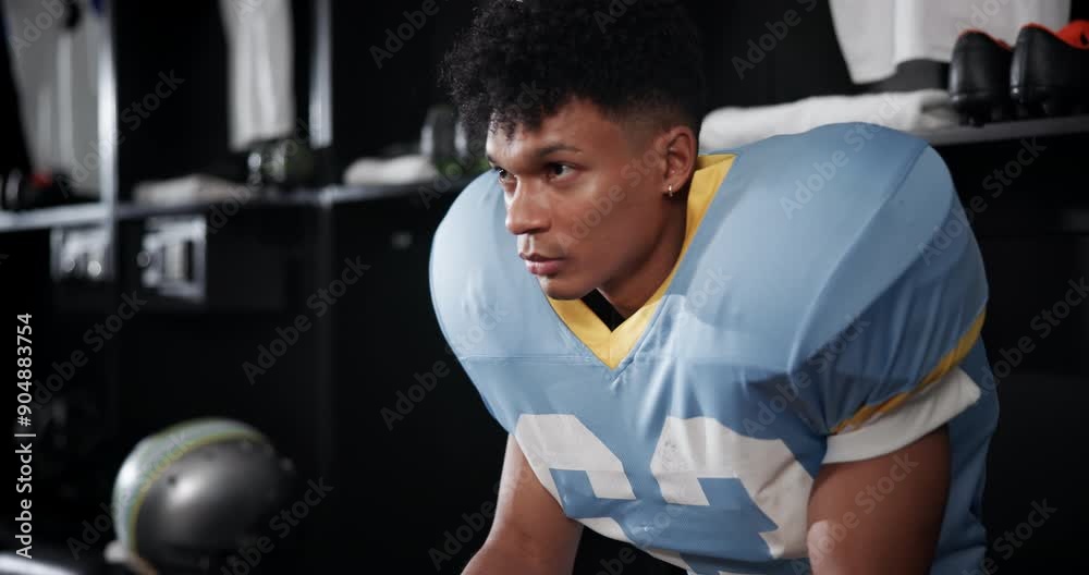 Black man, football and serious player thinking with ball in locker room for match, game plan or half time. Young African or athlete getting ready or preparation for sports tournament or competition