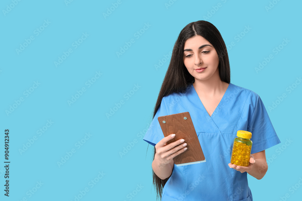 Beautiful young female doctor with clipboard and pills on blue background Beautiful young female doctor with clipboard and pills on blue background