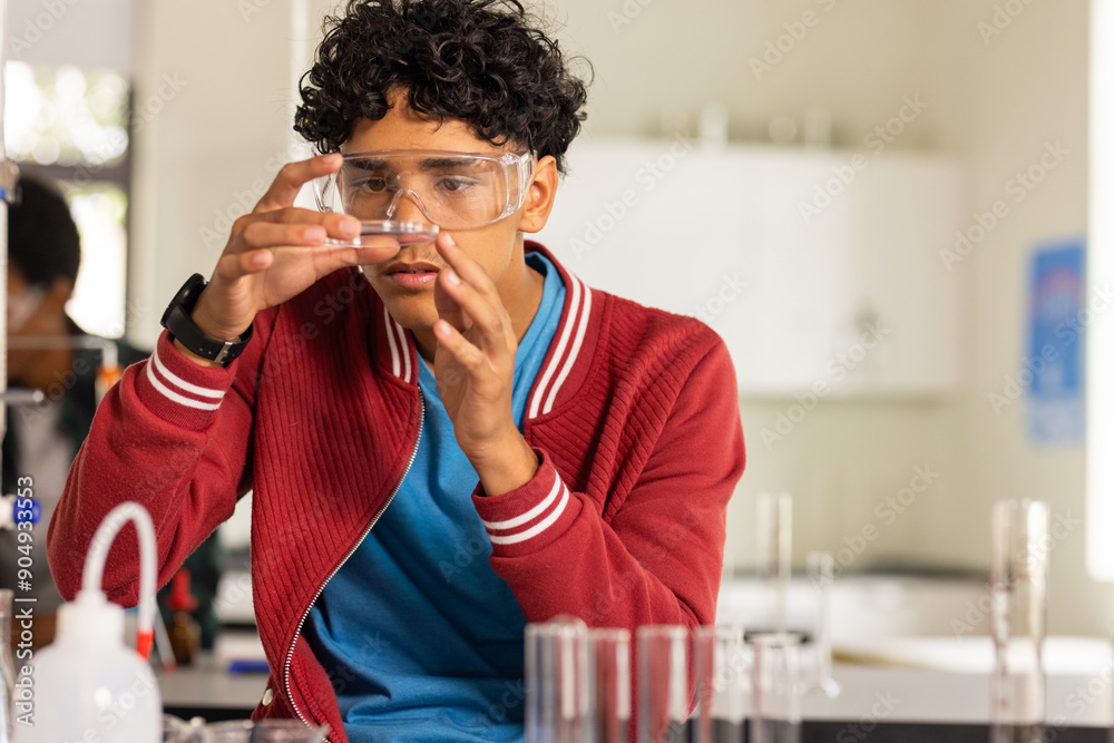 © wavebreak3 - In high school, teenager examining test tube in science classroom, wearing safety goggles © wavebreak3 - In high school, teenager examining test tube in science classroom, wearing safety goggles
