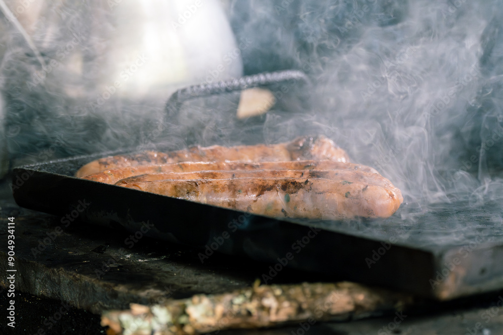 Close-up of sausages grilling on a smoky grill, creating a rustic and flavorful cooking scene Close-up of sausages grilling on a smoky grill, creating a rustic and flavorful cooking scene