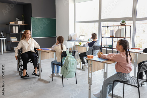 Mature teacher in wheelchair conducting lesson at school