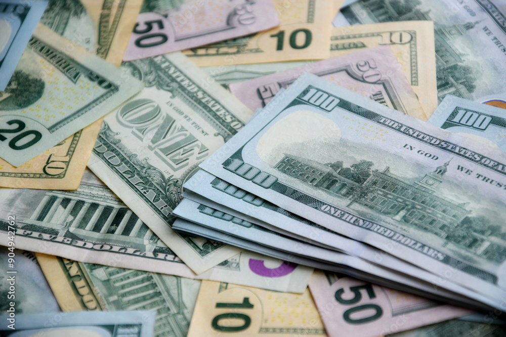 Big amount of US dollar bills in different nominations on table. Many dollar banknotes under natural light Big amount of US dollar bills in different nominations on table. Many dollar banknotes under natural light