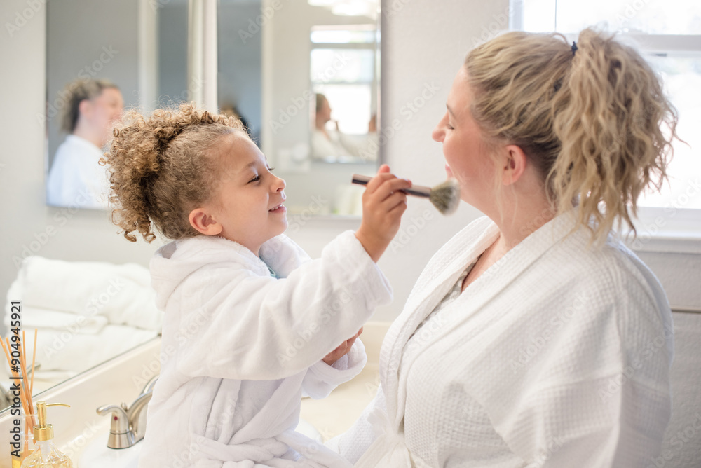 Daughter is brushing make up on mothers face in the bathroom Daughter is brushing make up on mothers face in the bathroom