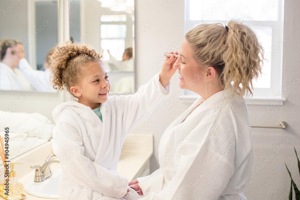 Little daughter is brushing make up on to mothers face in the bathroom Little daughter is brushing make up on to mothers face in the bathroom