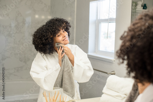 Biracial teenager is looking in the mirror wiping her face