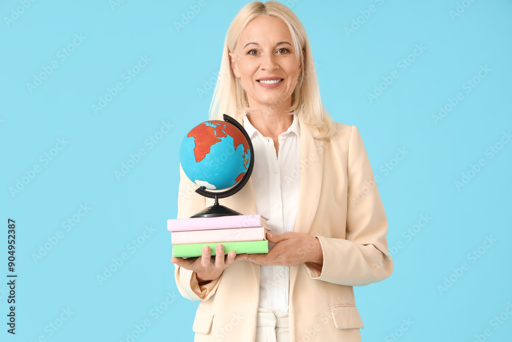 Fototapeta premium Female geography teacher with globe and books on blue background