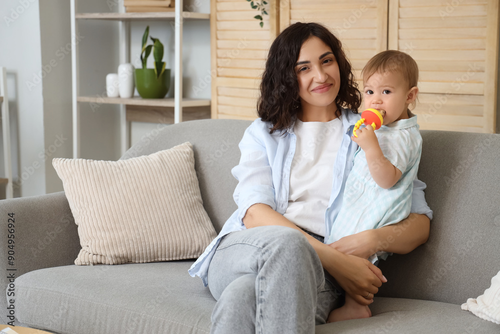 Mother and her little baby with nibbler eating food on sofa at home Mother and her little baby with nibbler eating food on sofa at home