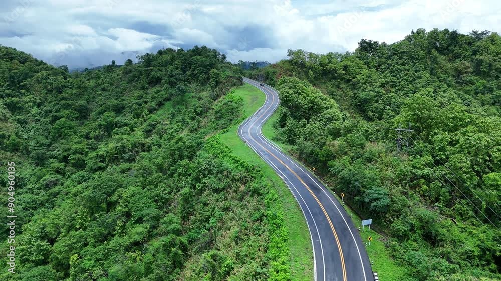 Aerial view highway Drone flying above winding road during sunlight, Winding asphalt road through tropical rainforest. countryside landscape. Landmark tourist attractions in Nan Province, Thailand. Aerial view highway Drone flying above winding road during sunlight, Winding asphalt road through tropical rainforest. countryside landscape. Landmark tourist attractions in Nan Province, Thailand.
