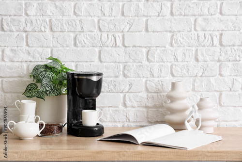 Modern coffee machine with cup, beans and open book on table in kitchen photo