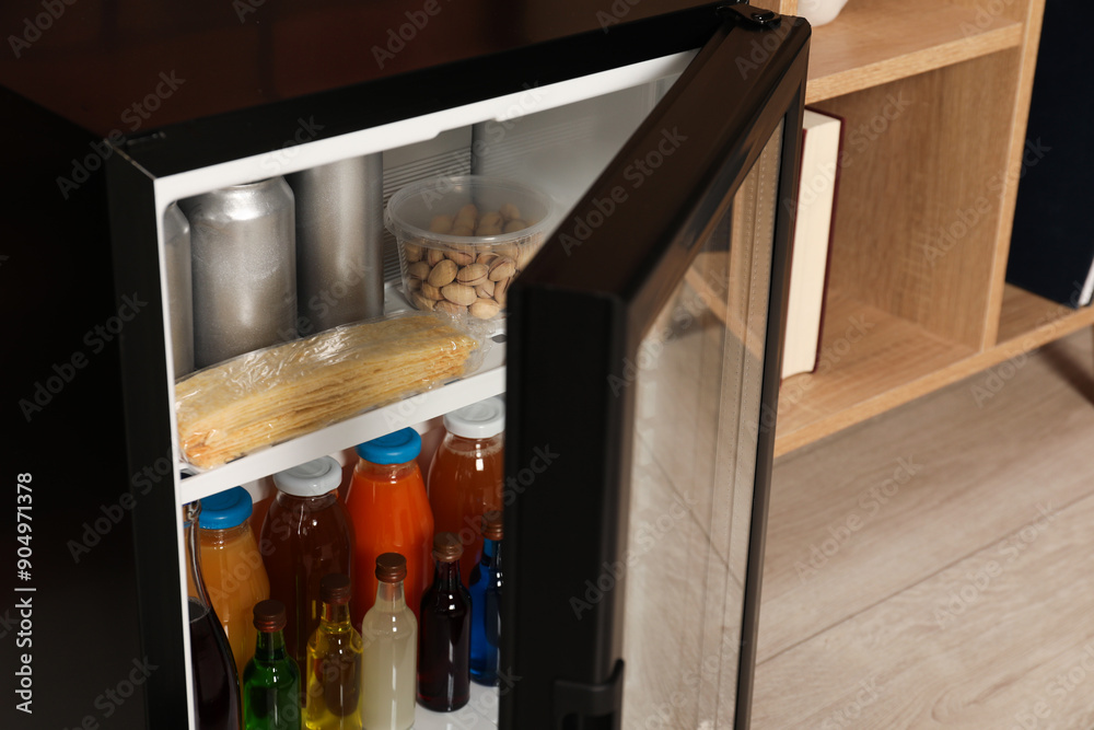 Mini refrigerator with drinks and snacks indoors, closeup Mini refrigerator with drinks and snacks indoors, closeup