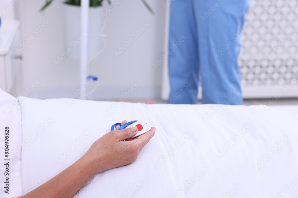 Senior woman with emergency call button and nurse setting IV drip in hospital, closeup Senior woman with emergency call button and nurse setting IV drip in hospital, closeup
