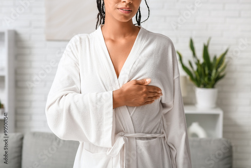 Young woman in bathrobe checking her breast at home. Cancer awareness concept