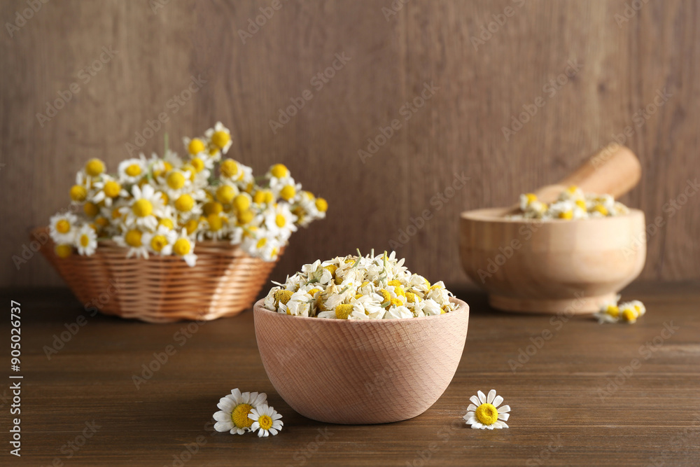 Dry and fresh chamomile flowers in bowl on wooden table Dry and fresh chamomile flowers in bowl on wooden table