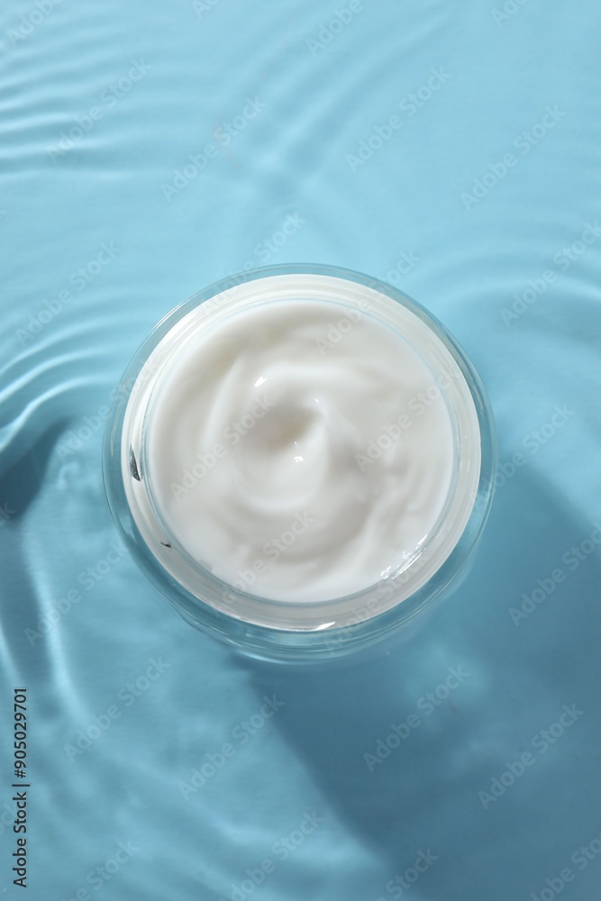 Jar with face cream in water on light blue background, top view Jar with face cream in water on light blue background, top view