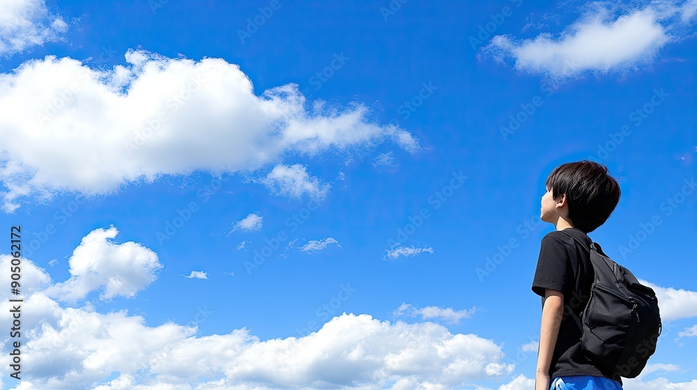A Young Boy Gazes Up at the Bright Blue Sky With Clouds A Young Boy Gazes Up at the Bright Blue Sky With Clouds