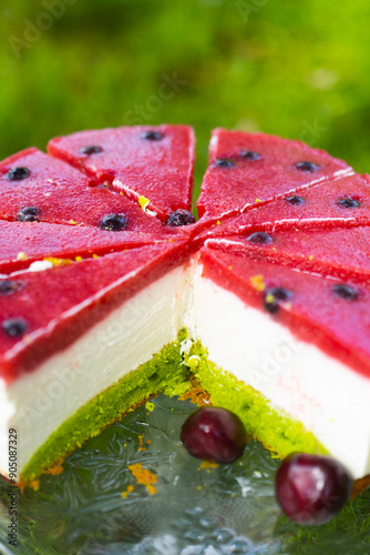 Homemade birthday mousse cake looks like watermelon made of cream cheese and strawberry confit on green grass