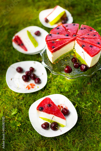 Homemade birthday mousse cake looks like watermelon made of cream cheese and strawberry confit on green grass