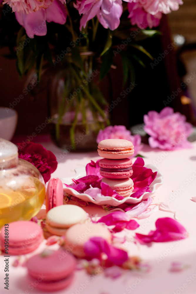 macaroni cookies on a plate, next to a teapot with tea. Pink tablecloth and flowers on the table macaroni cookies on a plate, next to a teapot with tea. Pink tablecloth and flowers on the table