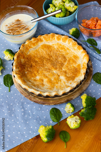 The process of making homemade French quiche pie with broccoli, spinach and salmon on blue plate