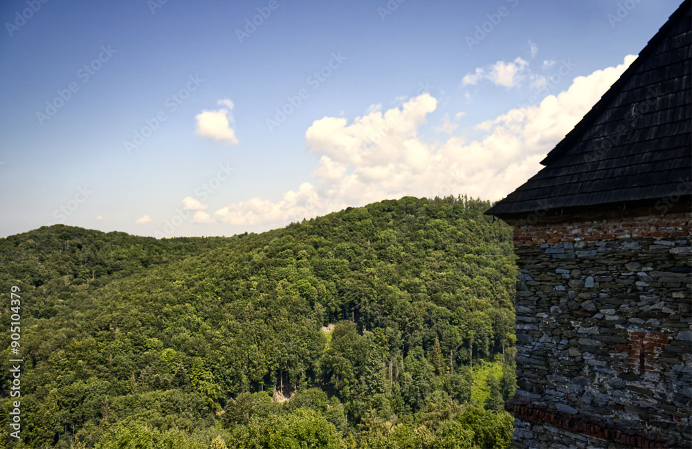 Fototapeta premium photos of hills with forests and parts of the tribal castle building. Part of the castle and a view of the surrounding countryside. Forest, trees, hills, nature, blue sky with clouds.