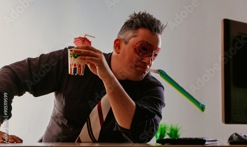 Businessman wearing a party mask drinking alone in office. Alcoh photo