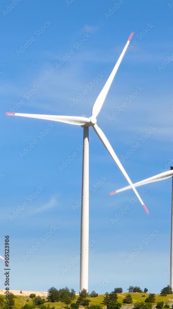 Vertical Screen: Windmills Rotating on a Sunny Day with a Sky Background in Slow Motion. Concept of Renewable Energy, Sustainability, Clean Power, Green Technology, Environmental Conservation Vertical Screen: Windmills Rotating on a Sunny Day with a Sky Background in Slow Motion. Concept of Renewable Energy, Sustainability, Clean Power, Green Technology, Environmental Conservation
