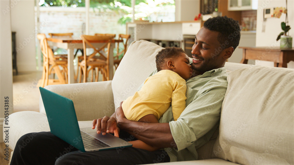 Father Comforts Sleeping Baby While Working on Laptop in Bright Living Room Father Comforts Sleeping Baby While Working on Laptop in Bright Living Room