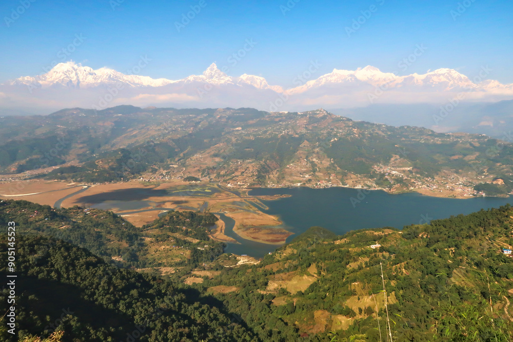 Fototapeta premium View onto Phewa Lake in front of a mountain range with Mount Machapuchare in the middle, on the way up to the World Peace Pagoda close to Pokhara, Nepal