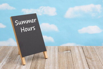  Summer Hours on a chalkboard easel on a table with sky