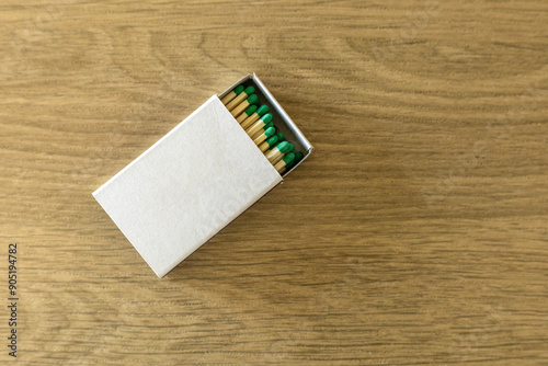 White cardboard box with green matches matchbox on wooden surface. copy space mock up concept